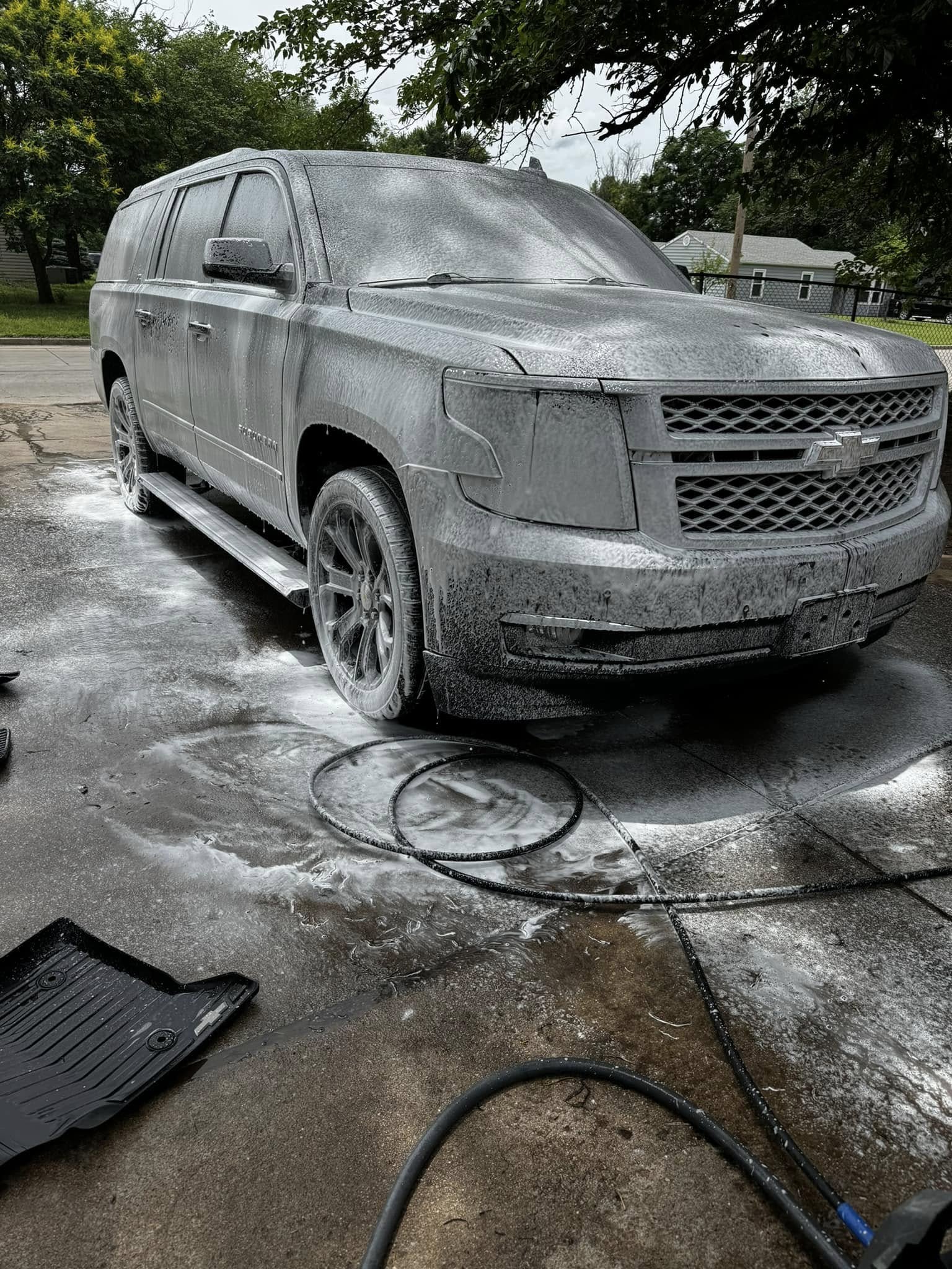 Black Cadillac SUV covered in wash foam during exterior detailing